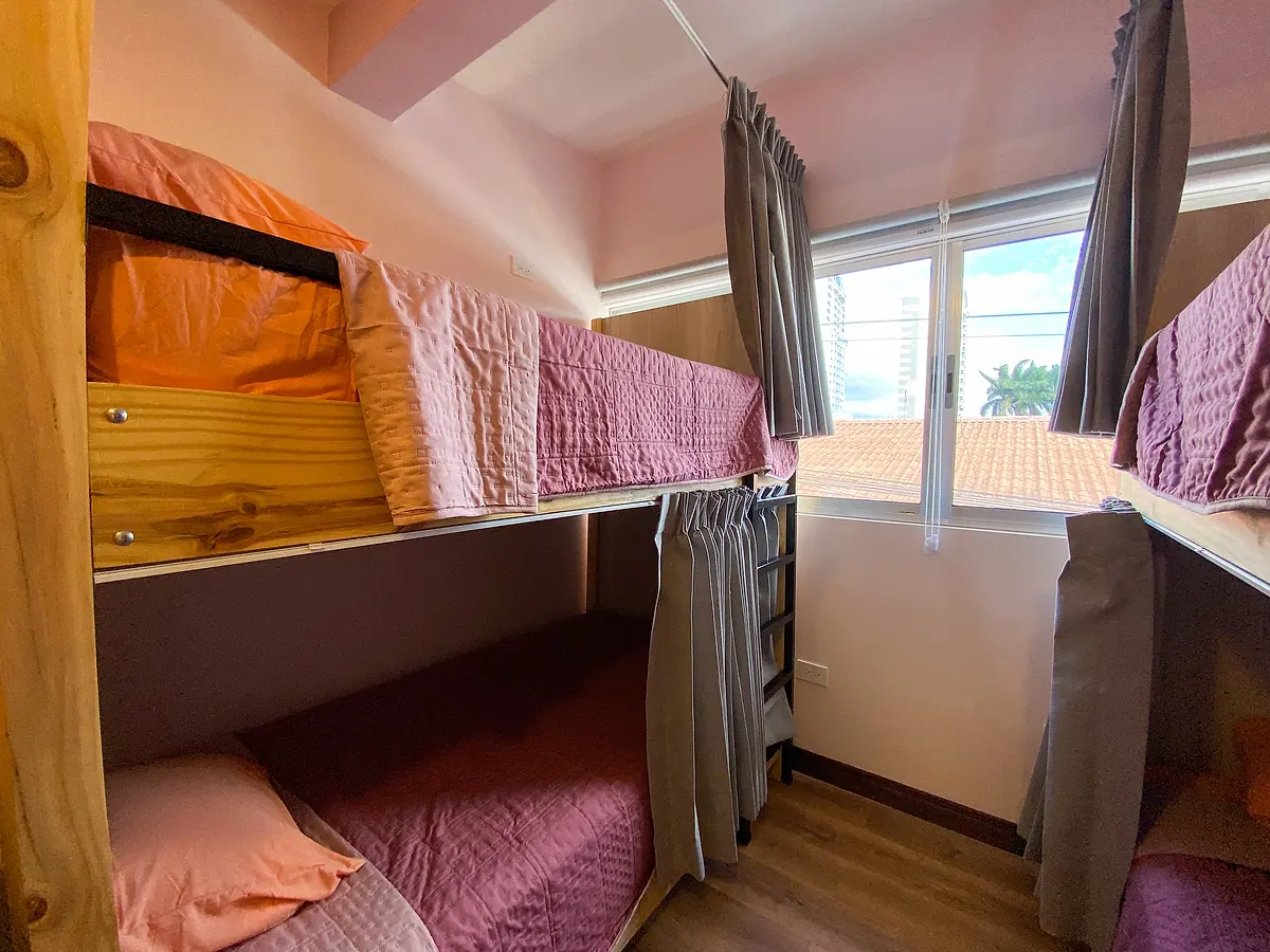 Bunk beds between wooden partitions, each bunk with its own grey blackout curtain