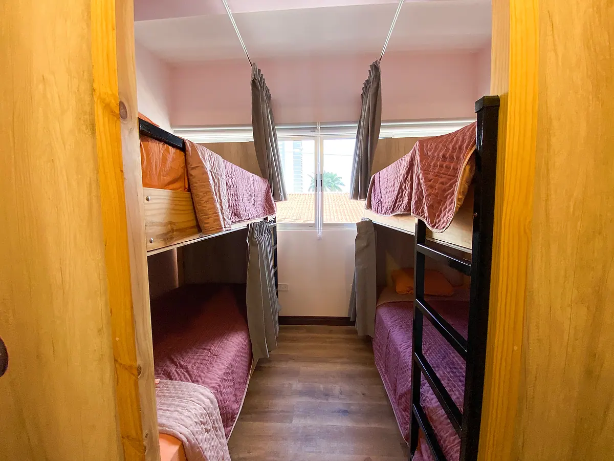 Two bunk beds under the window with pink covers and privacy curtains