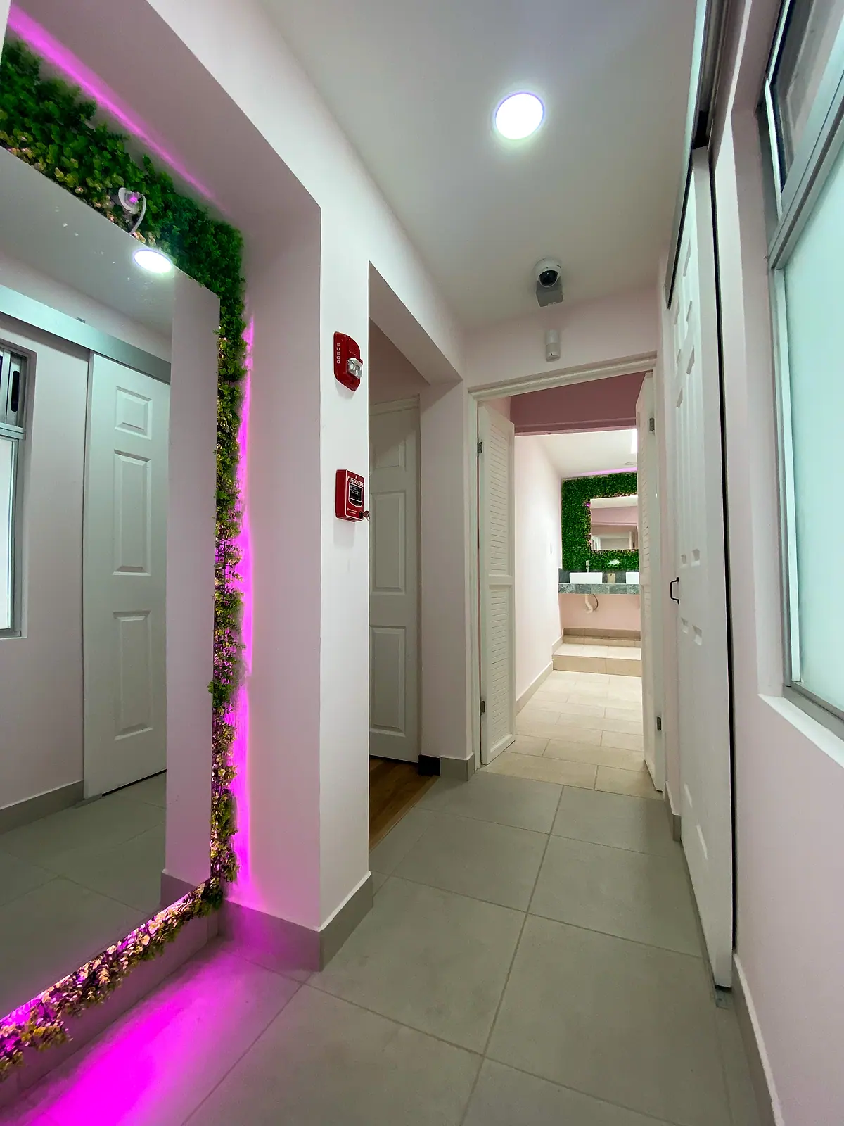 Bright hallway with a full-length mirror framed in pink neon
