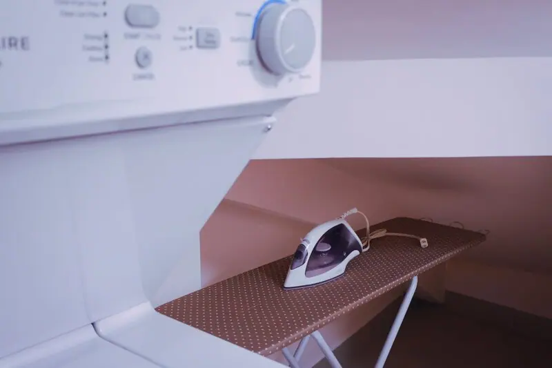 Iron resting on the ironing board beside the dryer controls