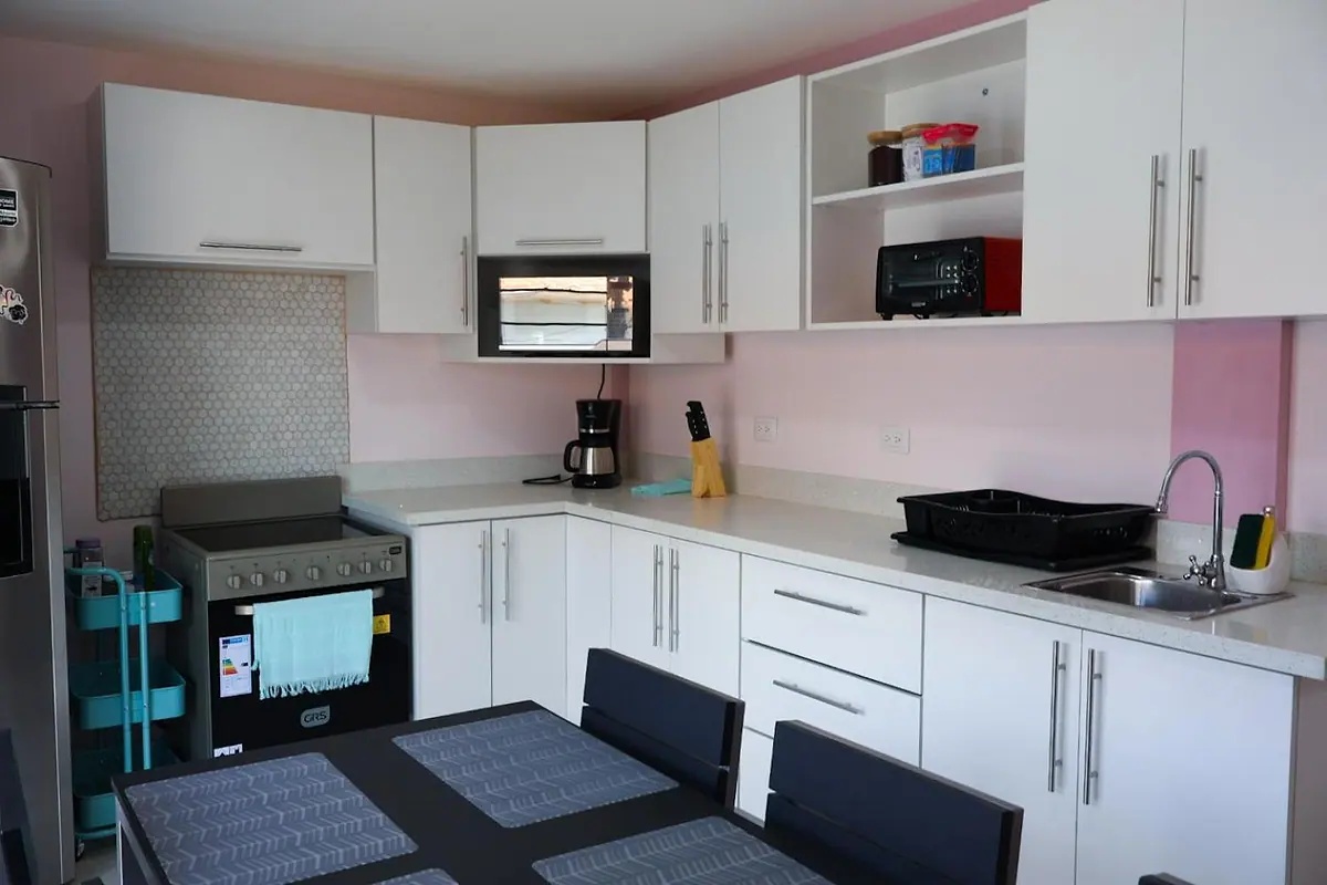 Kitchen counter with stove, microwave, coffee maker and sink above the dining table