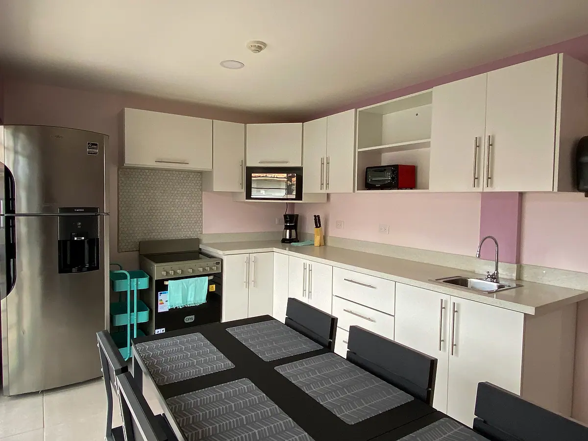 The kitchen: white cabinets, a stainless fridge, gas stove, microwave and the dining table