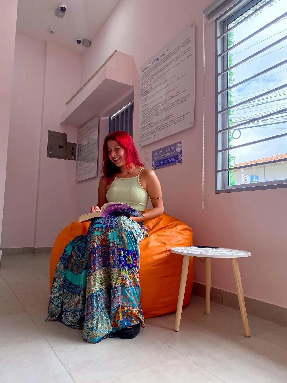 A guest with bright red hair reading on an orange beanbag by the lounge window