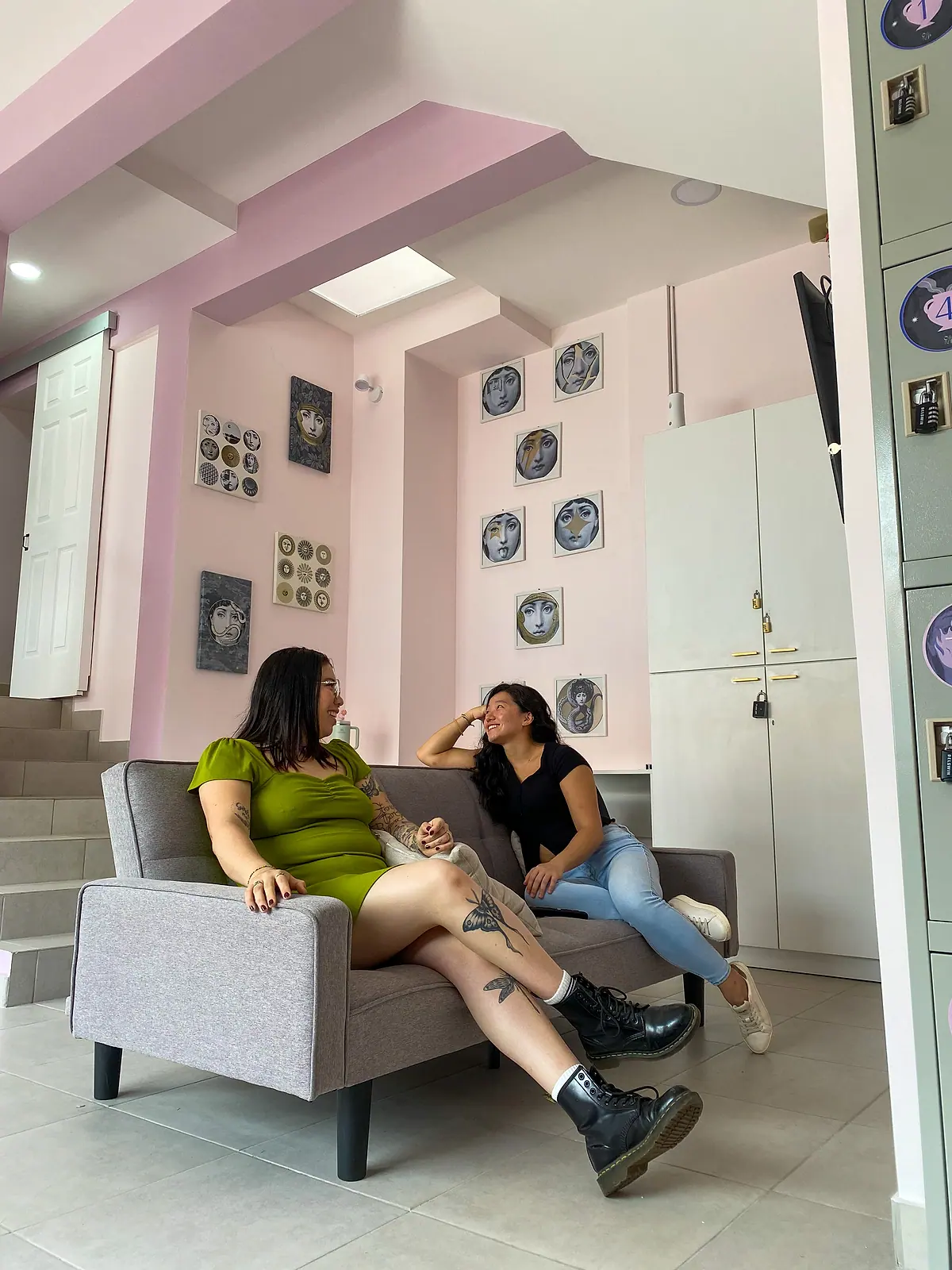 Two guests laughing on the grey lounge sofa under the wall of face plates