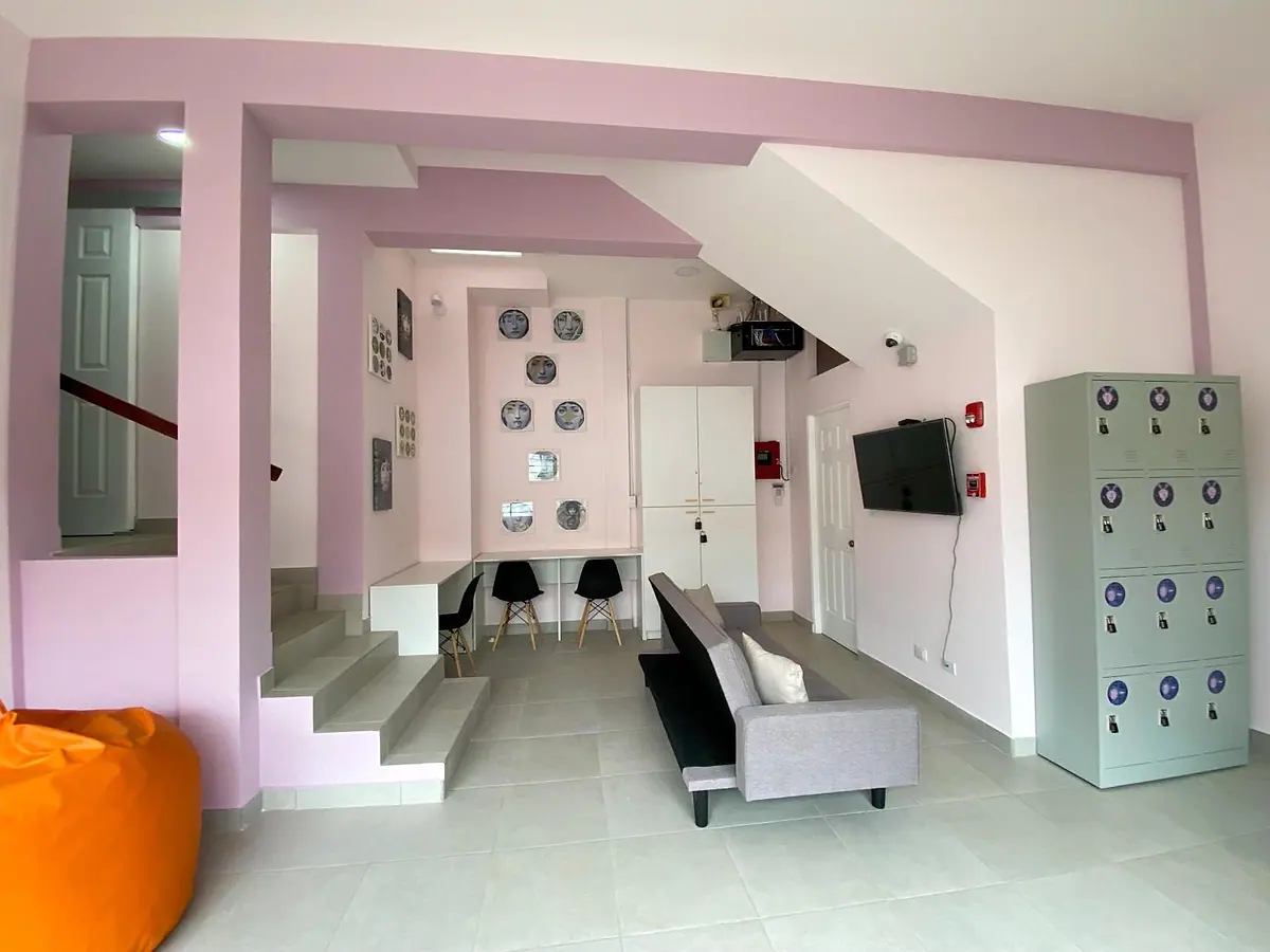 Lounge with the staircase, a sofa facing the TV, decorative face plates on the wall and lockers