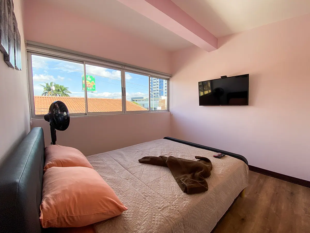 The queen bed facing the large window and the 50-inch TV in the Pandora room